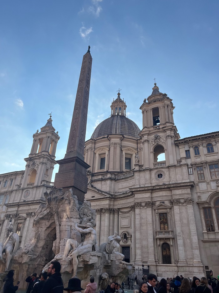 Buildings and fountains in Piazza Navona with people walking around