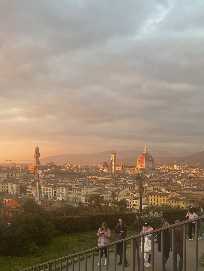 Sunset views over the city of Florence from Piazzale Michelangelo and people walking along a path