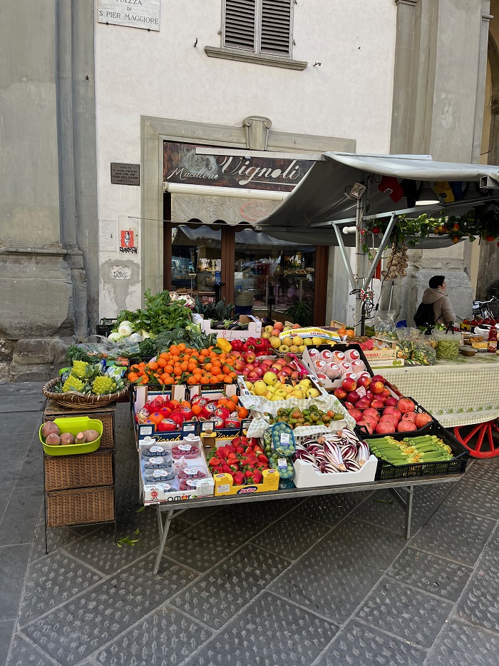Colorful fruits and vegetables organized on a table outside a fresh produce market in Florence. Italy