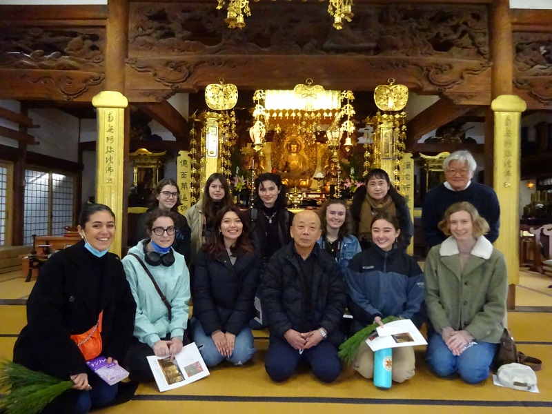 One of CET Japan's religion class with a sensei and local priests kneeling inside a Buddhist temple in Towaramoto, Nara, facing the camera