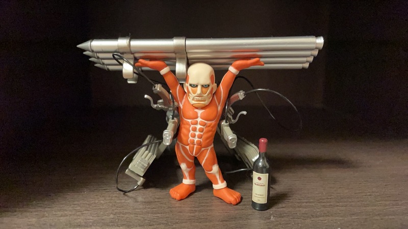 A small anime plastic toy of an Attack on Titan character holding four large missles