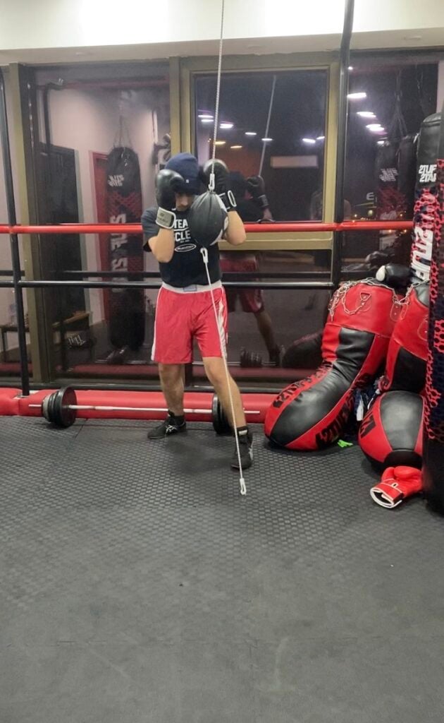 Someone holding his black boxing gloves by his face while practicing his technique in a boxing gym in Jordan