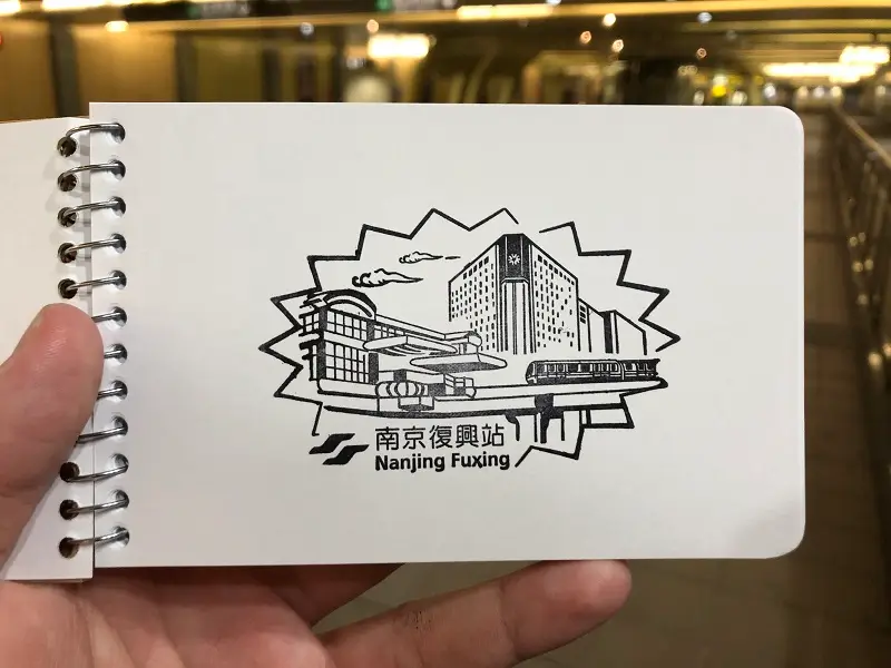 A black stamp of the Nanjing Fuxing Station of  the Brown Line portion of the station and the numerous office buildings that surround it