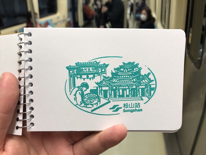 A green stamp of Songshan Station of the façade of the Songshan Ciyou Temple and the gate of the Raohe Street night market