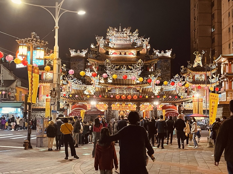 The outside of a busy Taiwan night with people crowded near the entrance 