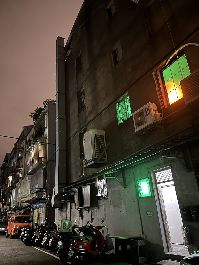 A street in Taipei, Taiwan with green illuminated lights from the inside of the building