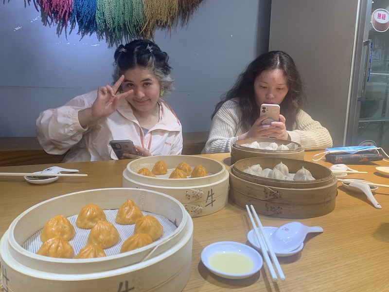 Two CET Taiwan students sitting in front of orange and white soup dumplings in a restaurant in Taiwan