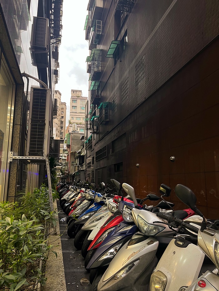 A row of motor bikes in a narrow street between buildings in Taiwan