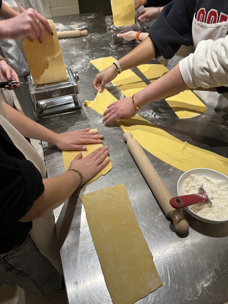 The hands of CET Florence students rolling out sheets of yellow dough to make pasta