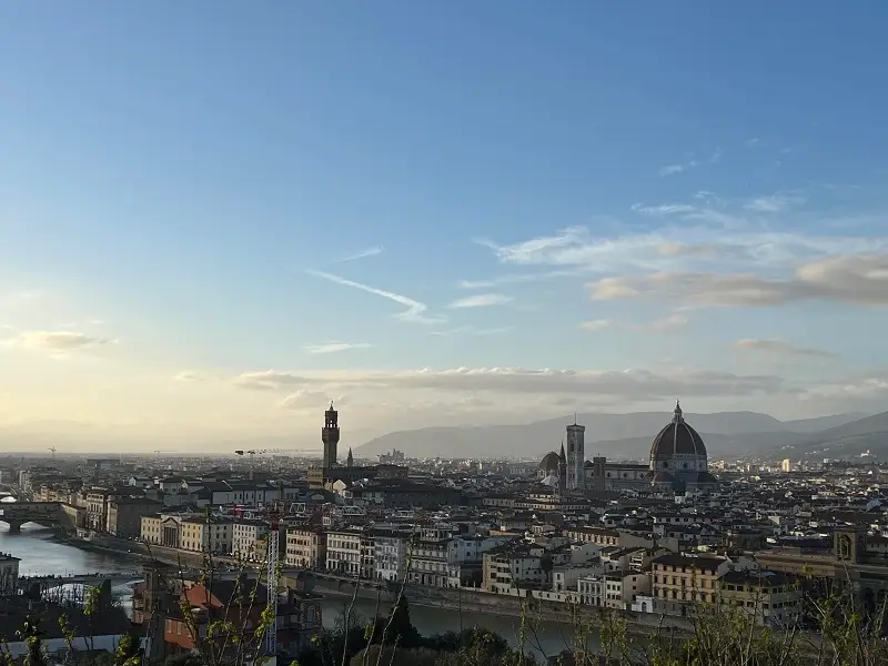 View from Piazzale Michelangelo of the Arno river and many buildings within the city of Florence and mountains in the far distance