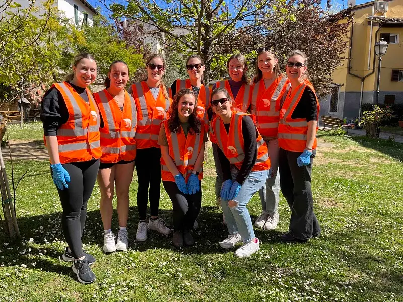 A group of CET Florence students smiling outside at a local garden in front of a tree in Florence, Italy