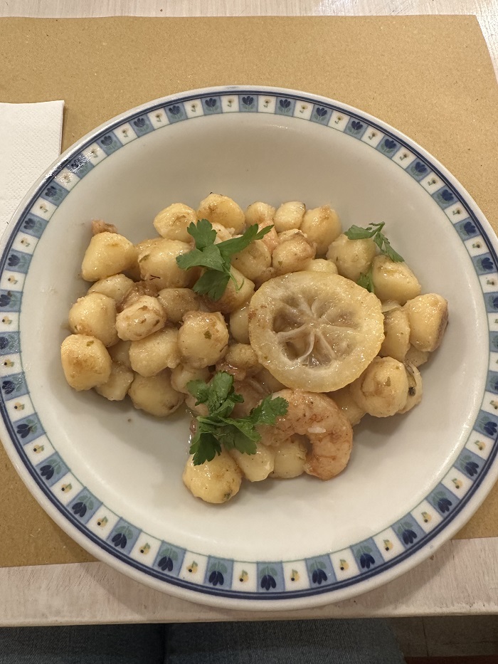 Shrimp and lemon gnocchi dish garnished with some greens on a small dish