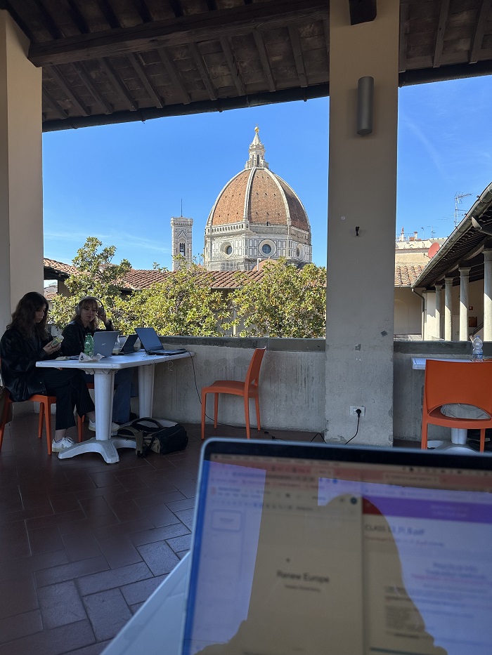 The inside of a public library with some desks and chairs and the view of the Duomo through a window in Florence, Italy