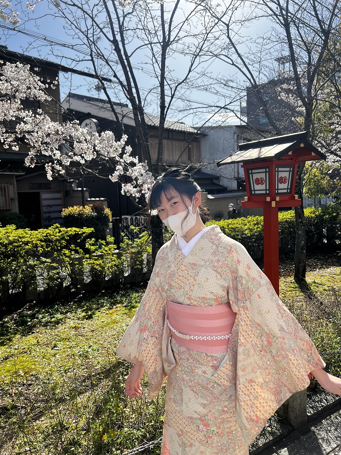 A CET Japan student wearing a kimono and mask outdoors on a sunny day in Kyoto, Japan