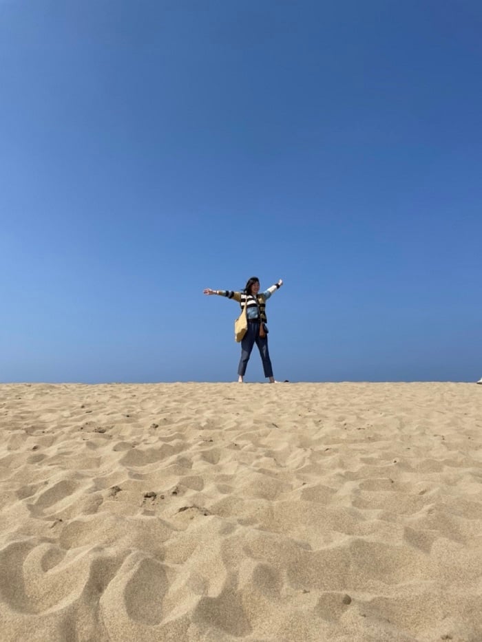 A CET Japan student holding up her arms on sand in Tottori Sand Dunes 