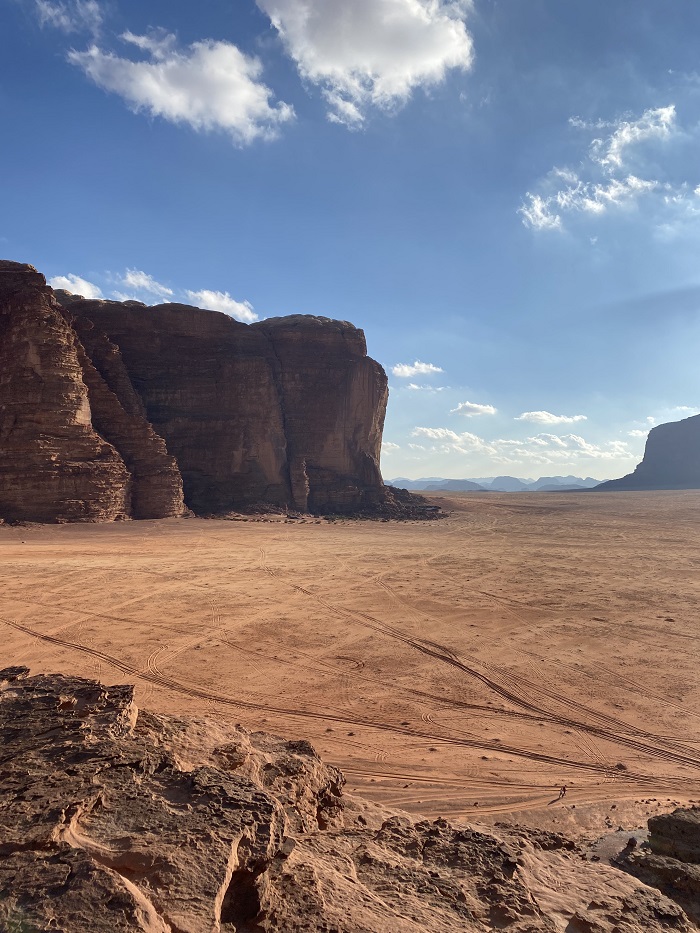 Giant rock formations amidst a desert landscape in Wadi Rum, Jordan on a sunny day with blue skies and some clouds