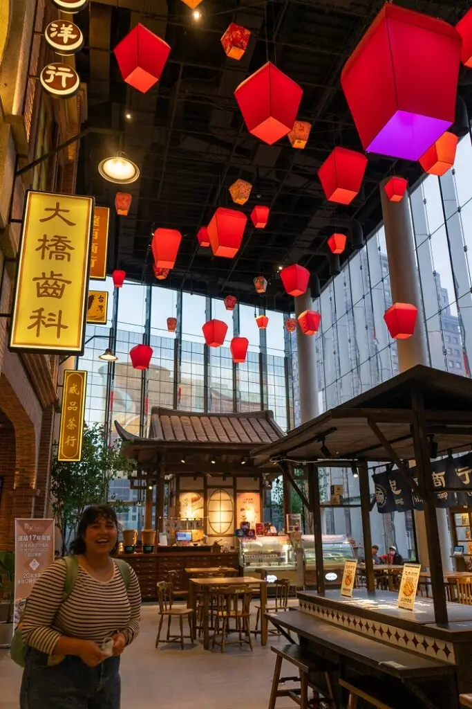 CET Taiwan roommate smiling in Chun Sui Tang Far Eastern Xinyi A13, a department store decorated with lanterns and traditional-looking tea shops