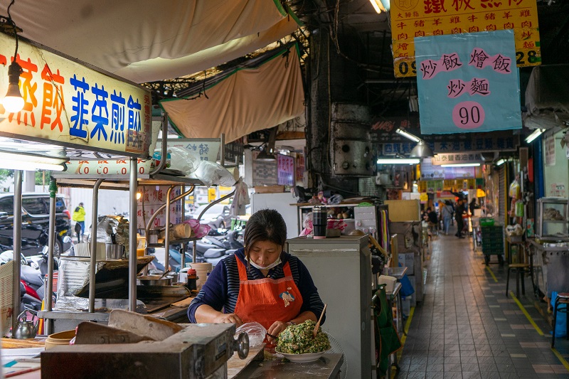 A narrow street with different food vendors on either side in Taiwan