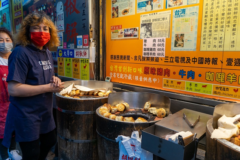 Two women looking towards the camera and standing by an outside food stand in Gongguan