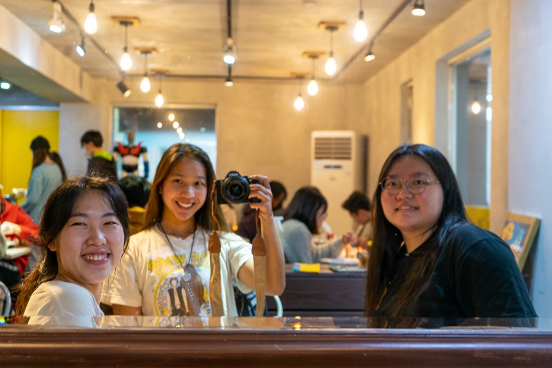 A CET Taiwan student, her language partner, and another CET Taiwan roommate smiling in front of a mirror at a Japanese restaurant 