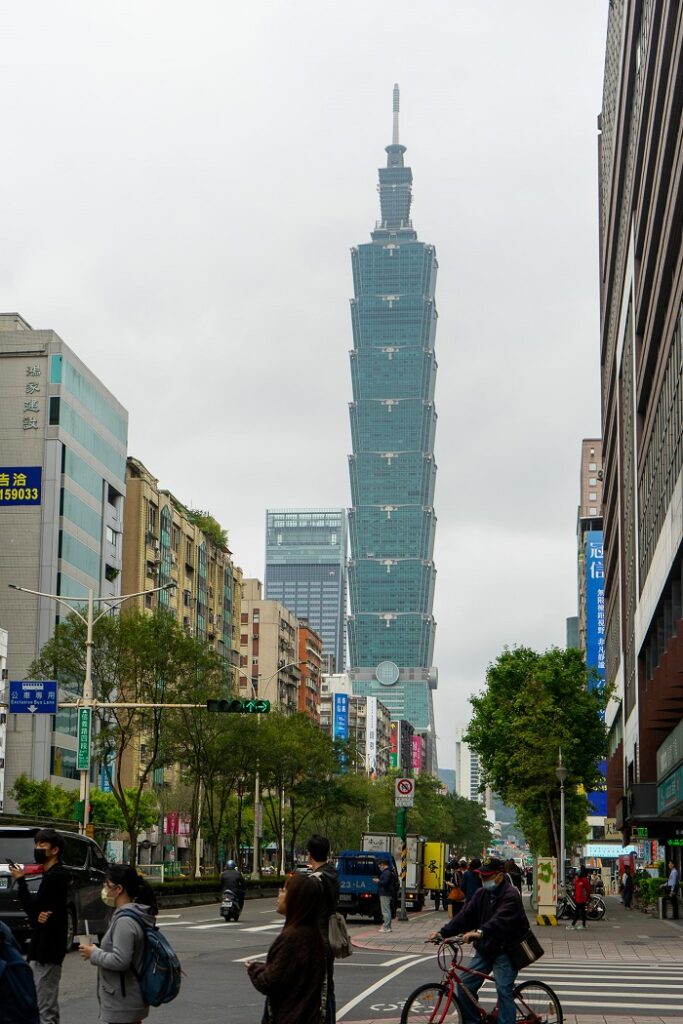Taipei 101 and other buildings in Taiwan with people walking and biking across a street