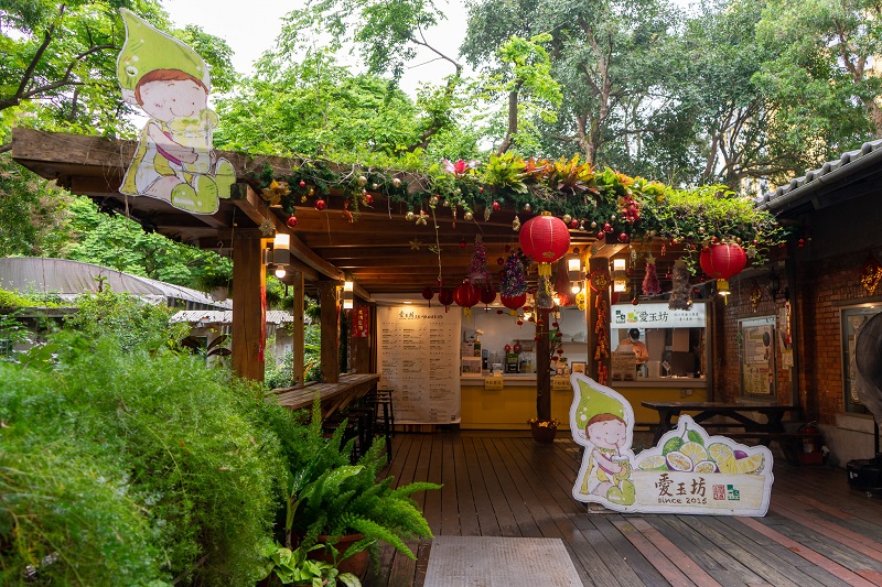 A small outdoor café at National Taiwan University with greenery and small ornaments hanging off of the roof along with red lanterns 