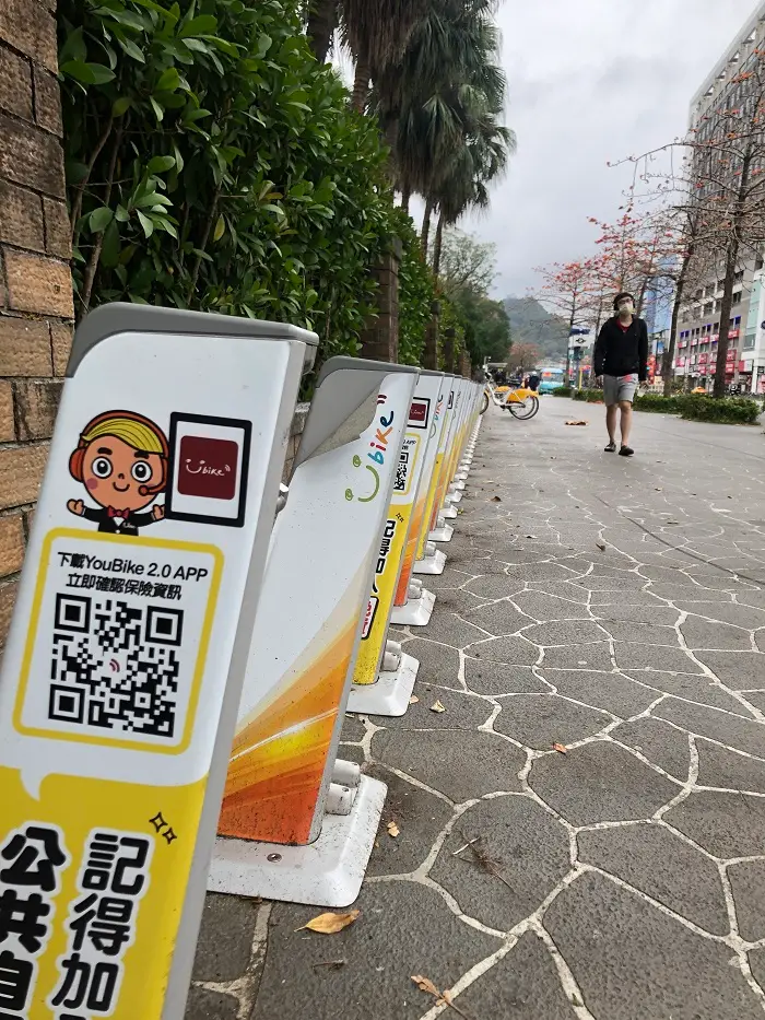 An almost empty YouBike station outside and a person walking on the street
