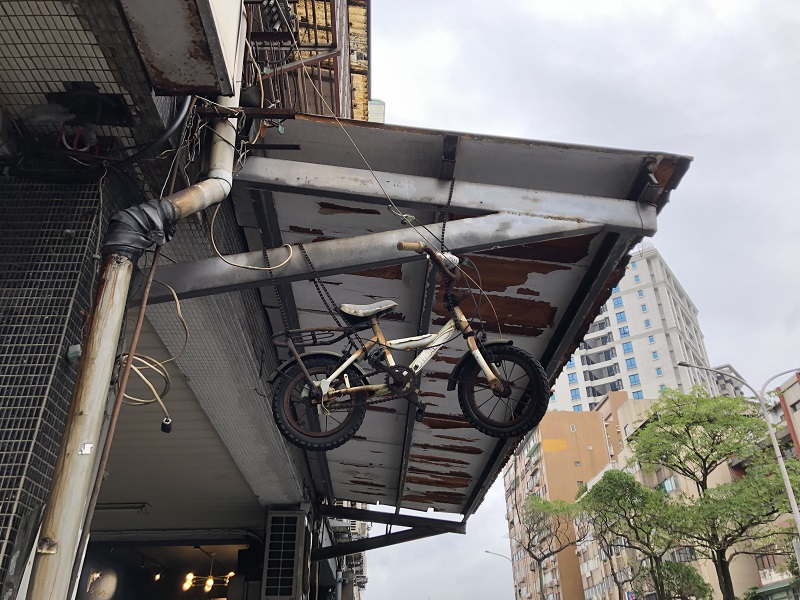 An old bike hanging outside off of an overhanging of a building
