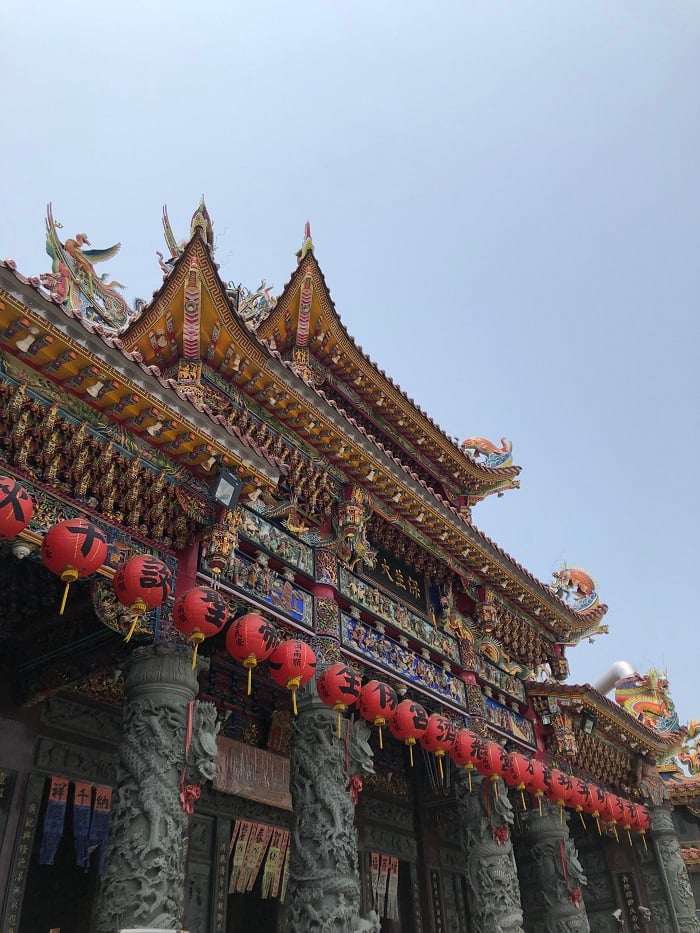 A close-up view of a temple in Kaohsiung with red lanterns hanging from the temple and colorful decorations 