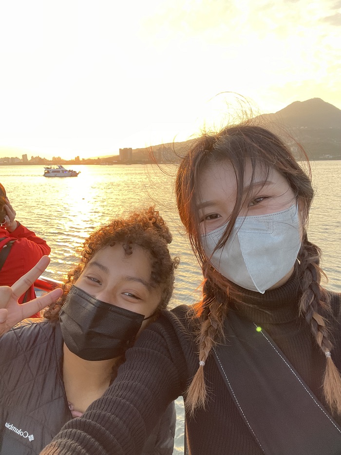 A CET Taiwan student and her friend wearing masks and taking a selfie on a boat on water