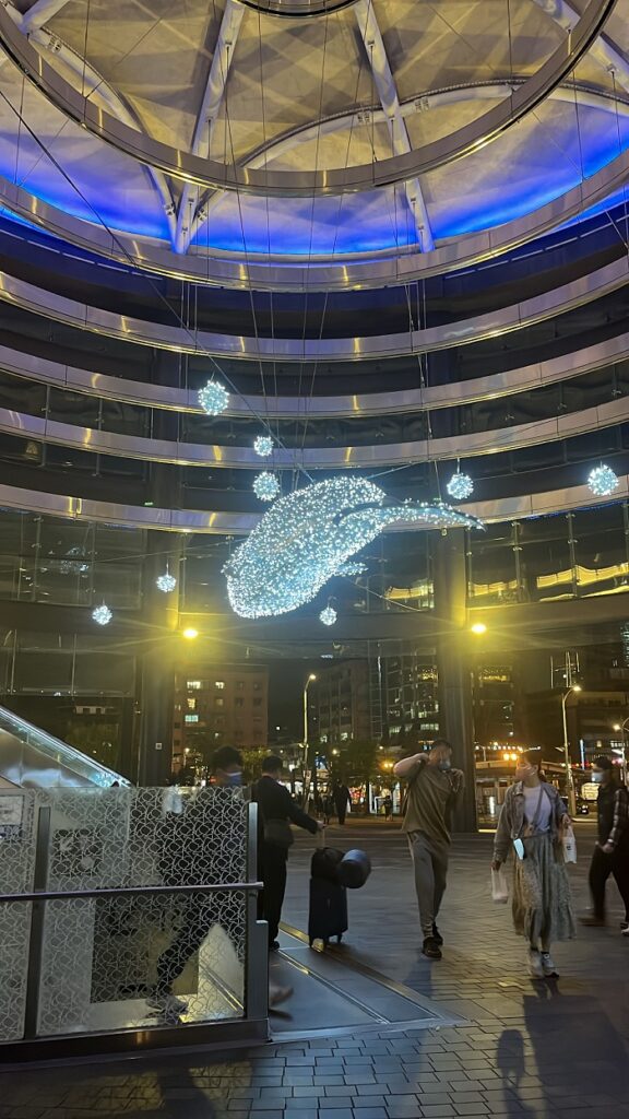 A giant moving light-up whale hanging above people at the Songshan station entrance