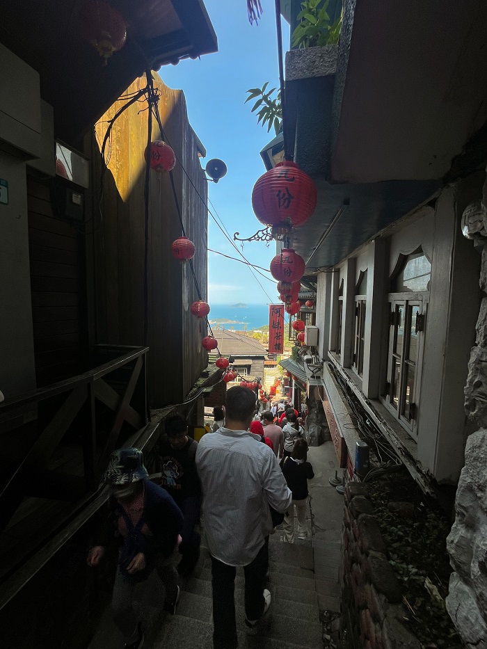 People walking down the narrow path of Jiufen that is lined with red lanterns handing from buildings in Taiwan