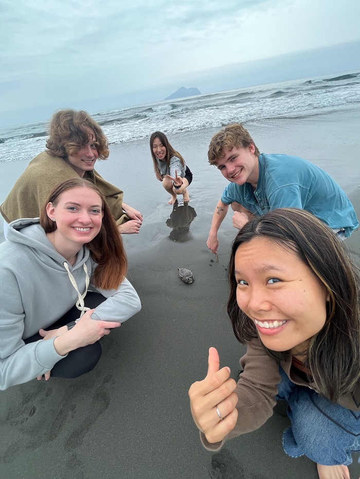 CET Taiwan students smiling and taking a selfie while crouching down on Waipao Beach