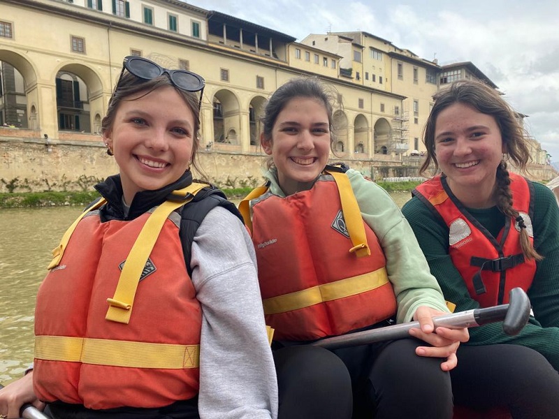 Three female CET Florence students smiling on a raft while in the Arno River