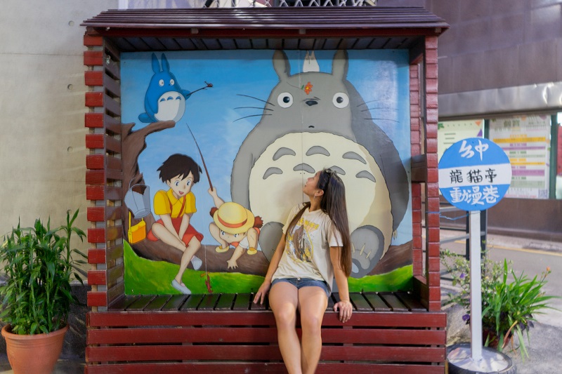 CET Taiwan student sitting and looking up at a little Totoro mural