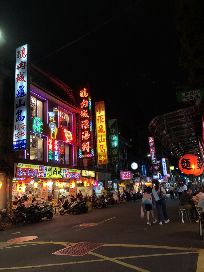 A street people walking and buildings with many bright neon signs in Taiwan