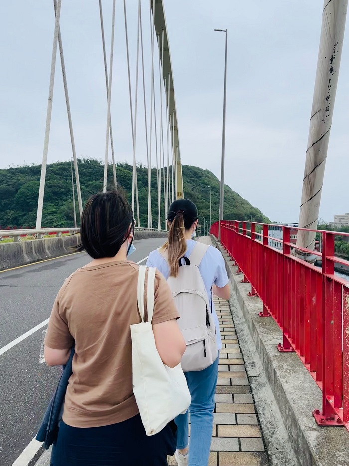 Two people walking across a bridge by a street in Taiwan