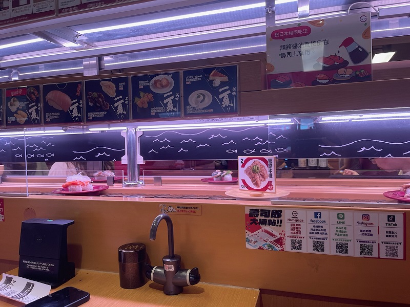 Sushi and other food items passing by on small plates on a conveyor belt in a restaurant in Taiwan