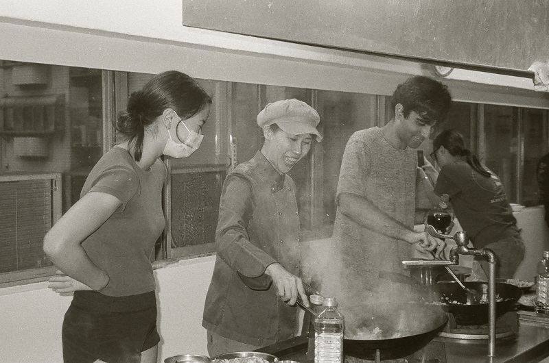 A woman stirring fried rice with other CET Taiwan students in a cooking class 