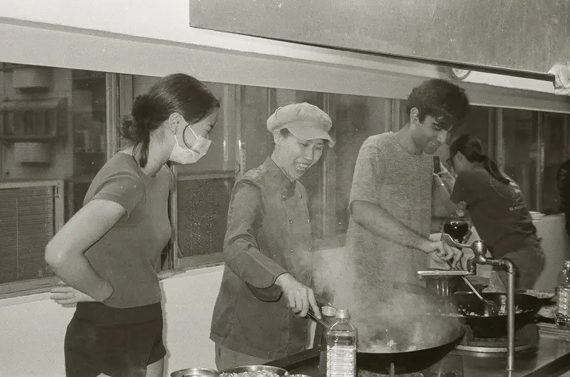 A woman stirring fried rice with other CET Taiwan students in a cooking class