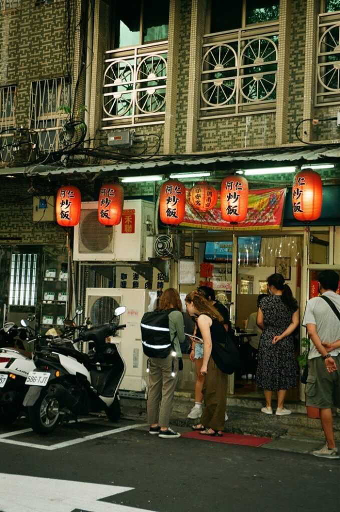 A small group of people waiting outside  a restaurant in Taiwan 