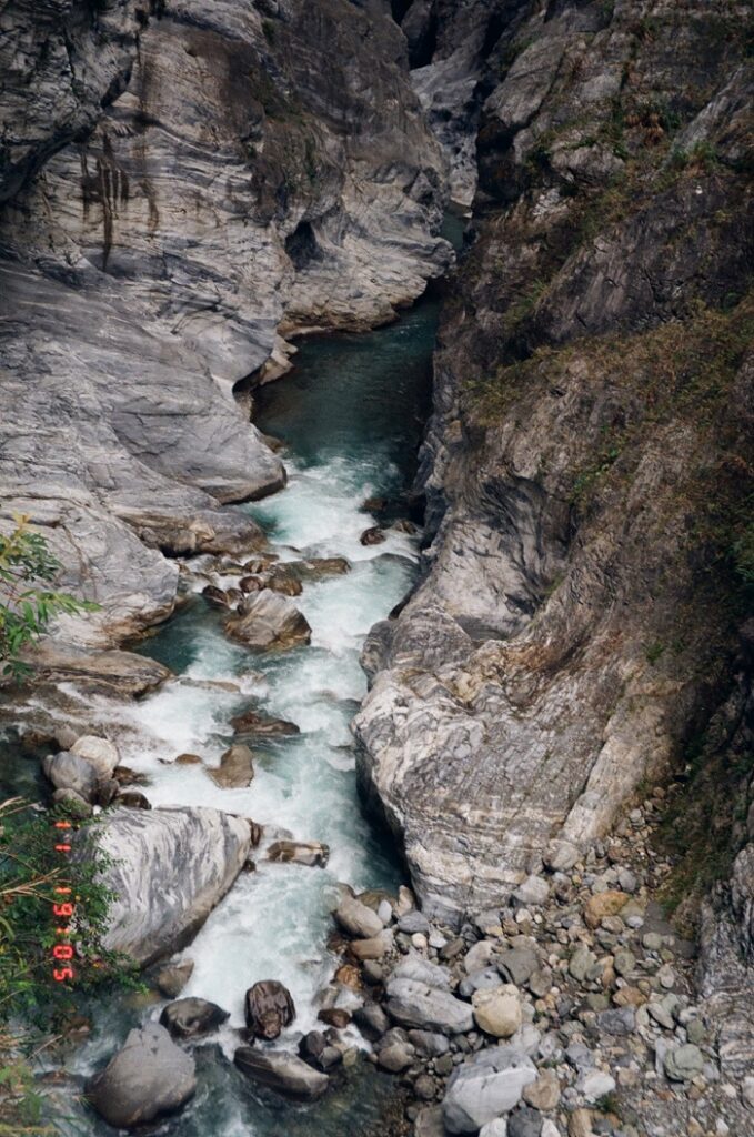 A river in Taroko National Park with rushing beautiful turquoise water amid small and large rocks