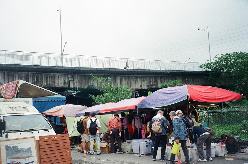 Tents set up outdoors with people looking through items at the Fuhe Flea Market in Taiwan