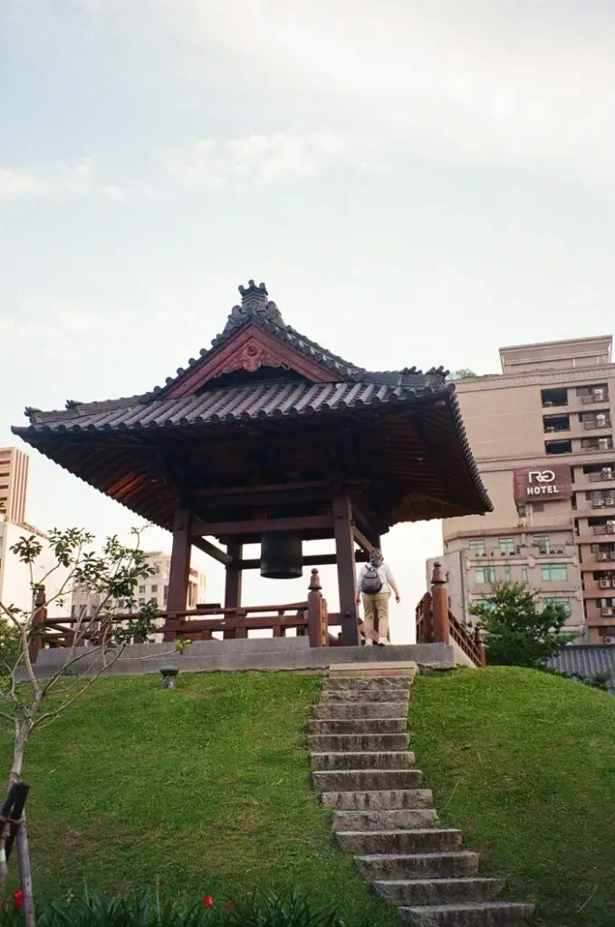 Somebody with a backpack walking up the stairs to a traditional Japanese Tea house right next to the Nishi Honganji Square