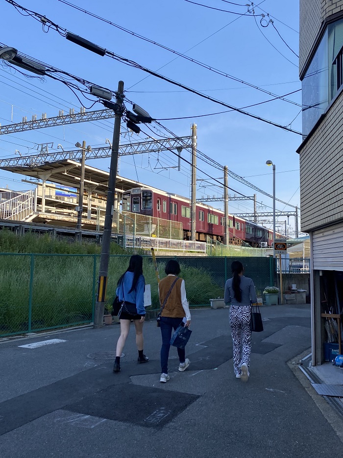 Three females walking outside in the street of Japan by a train station