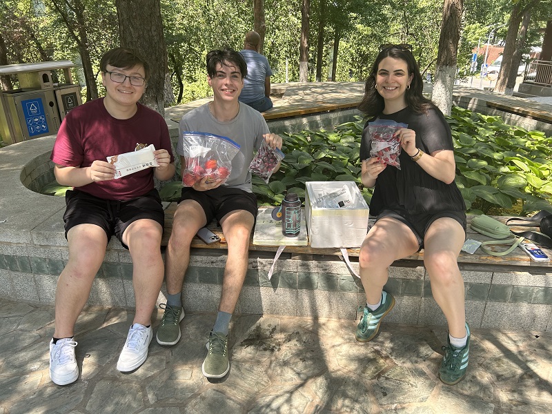 Some CET Beijing students holding up freshly delivered fruit at a park in Beijing, China