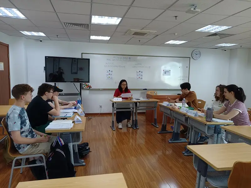 A small classroom debate with six CET Beijing students sitting across from one another and a professor sitting in the front of the classroom