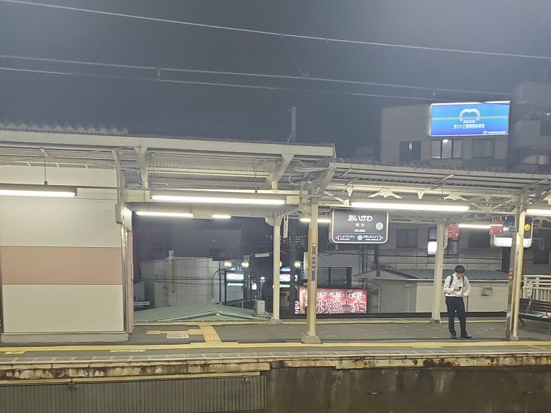 Someone standing while looking at his phone across a train platform at night in Japan