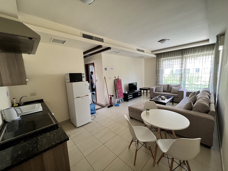 CET Jordan apartment with a simple kitchen, table and three chairs, couches, small fridge, and television