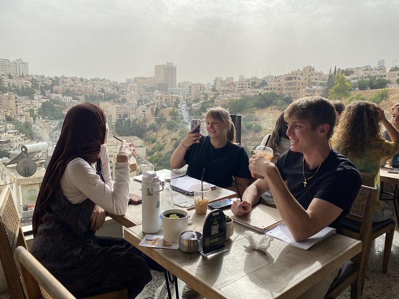 CET Jordan students and their Jordanian neighbors eating and drinking on the balcony of Manara Café